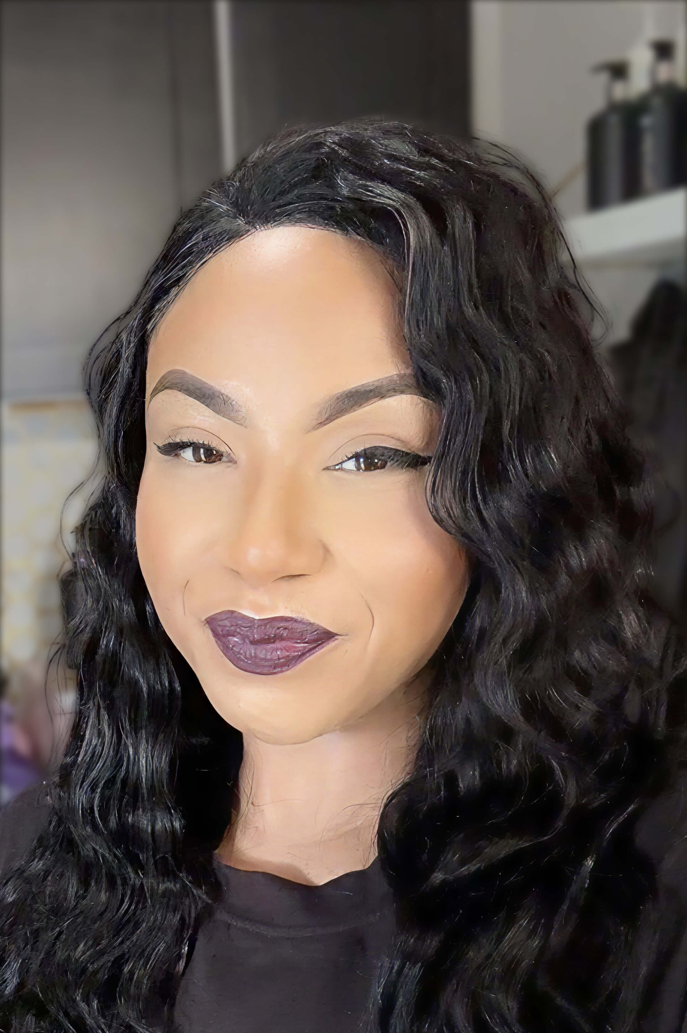 Closeup of woman with dark hair, manicured brows, and a bold, purple-hued lip